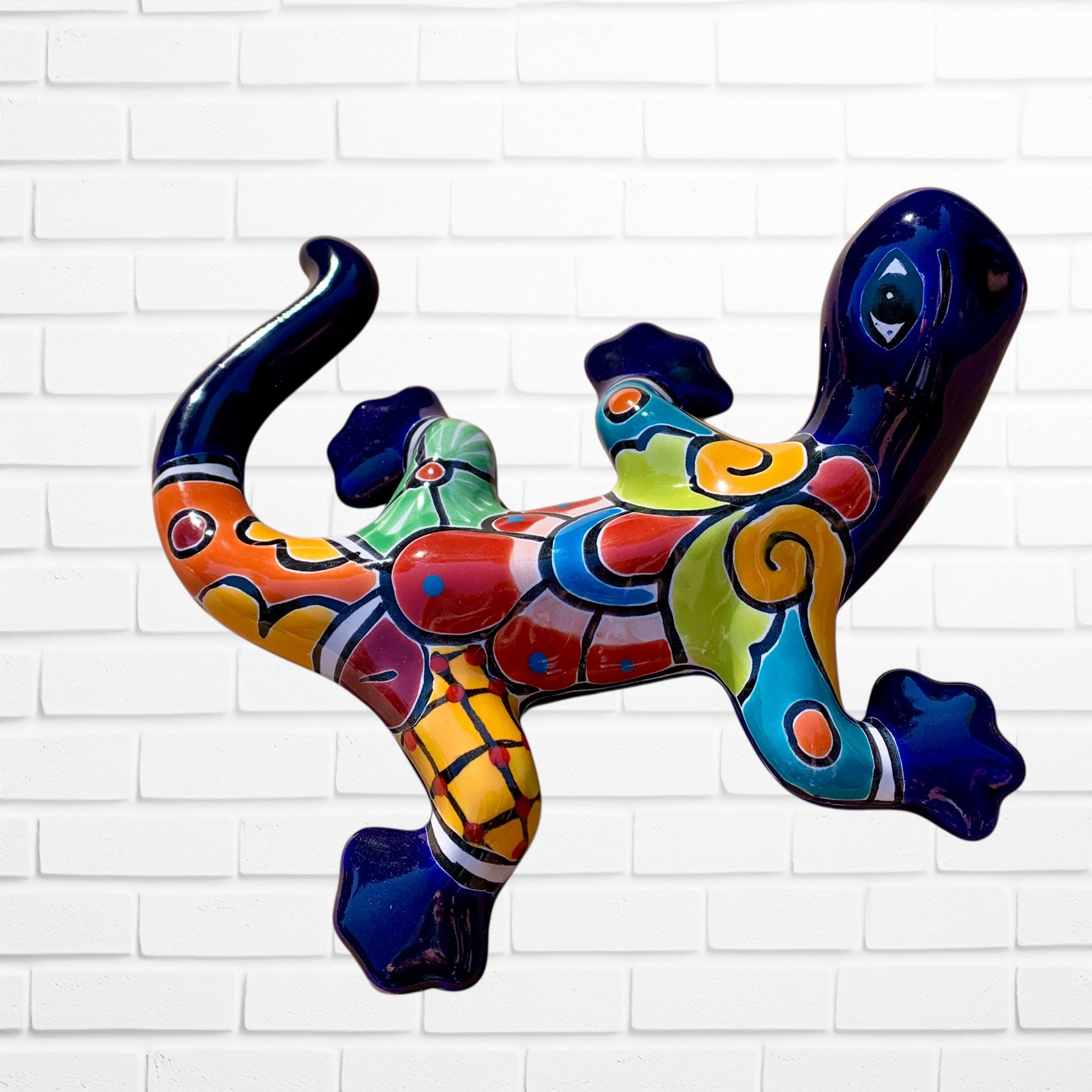 Colorful lizard-shaped wall art against a white brick wall background back side