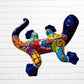 Colorful lizard-shaped wall art against a white brick wall background back side