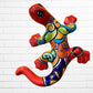 Colorful red ceramic lizard wall art against a white brick wall background