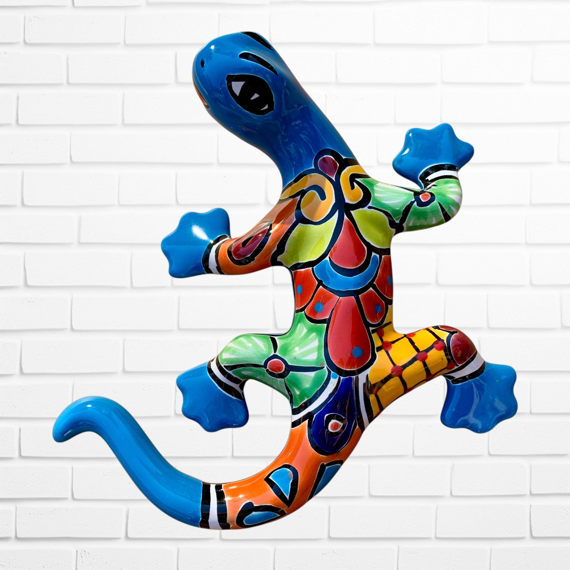 Colorful ceramic lizard wall art against a white brick wall background