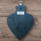 A Mexican Milagros large heart in black with a gold and red flaming top, covered in antiqued charms, back view.
