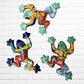 Three colorful ceramic wall-mounted frog sculptures in a vibrant multicolor design, displayed against a white brick wall background.