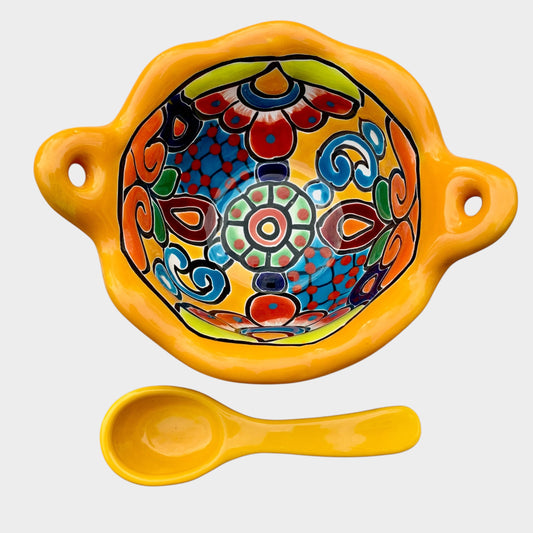 Colorful talavera salsa bowl with floral patterns and spoon on a white background