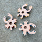 Three colorful hand-painted Talavera ceramic crabs arranged on a textured gray concrete surface back view showing hanging hole.
