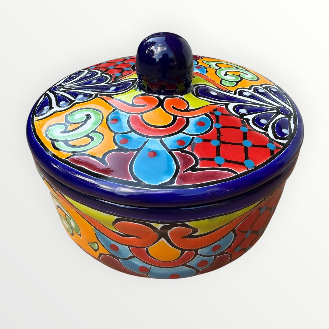Mexican covered tortilla serving piece with blue rim and multi-color designs. 