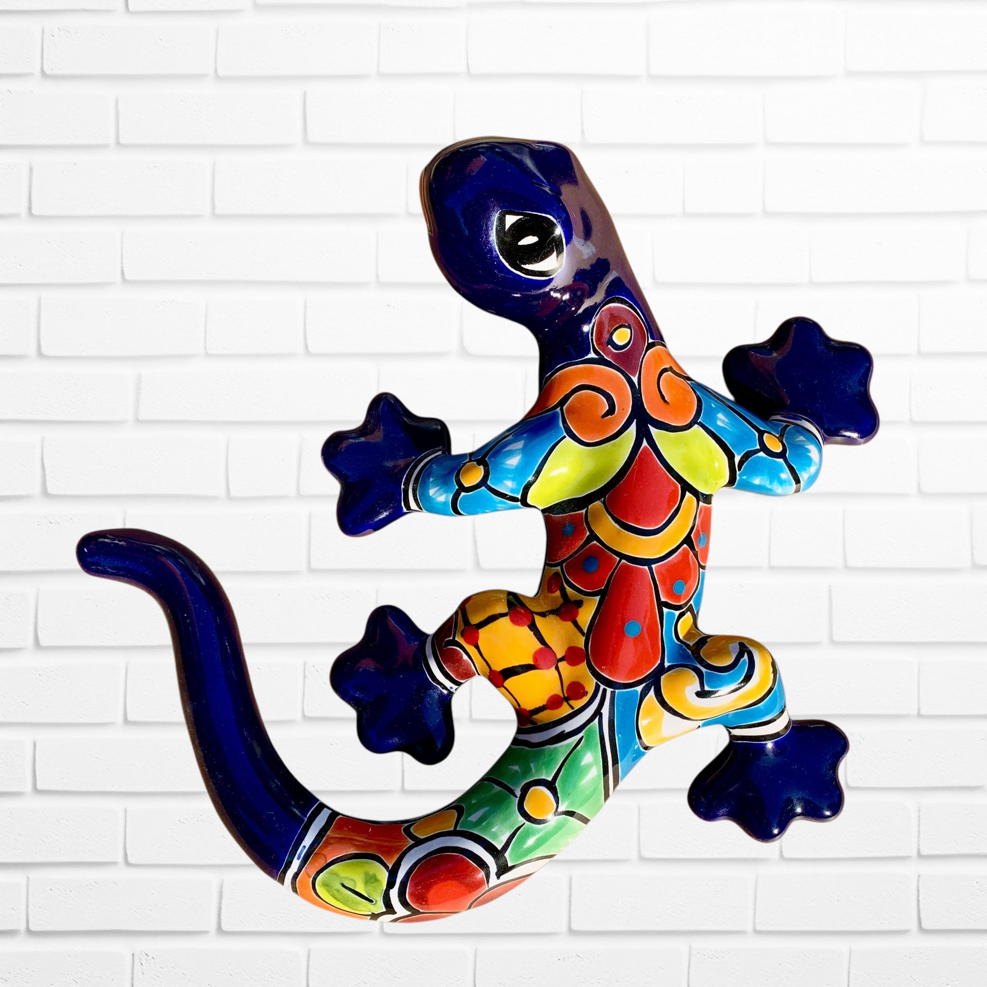 Colorful lizard-shaped wall art against a white brick wall background