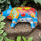 Colorful Talavera ceramic pig planter on a stone surface with green plants in  Background bottom drain hole.