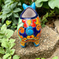 Colorful Talavera ceramic pig planter on a stone surface with green plants in  Back tail view