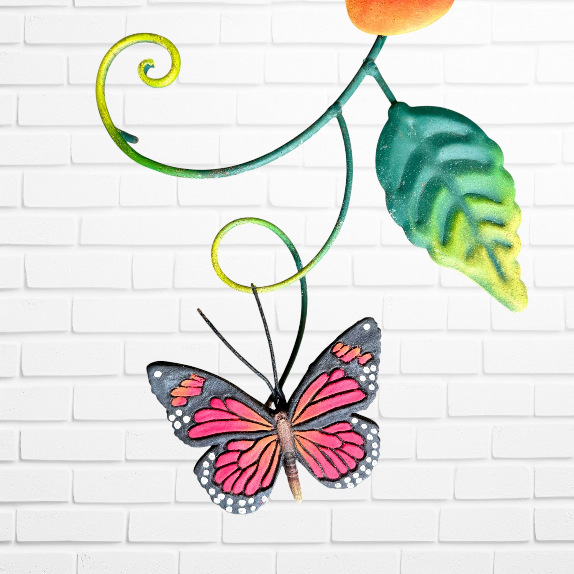 Decorative metal butterfly with pink wings on a white brick wall background bottom butterfly