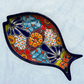 One blue decorative fish-shaped talavera dishes with colorful hand-painted floral patterns, displayed on a light blue textured background.