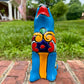 Coyote figurine on a brick surface with a garden background Front view