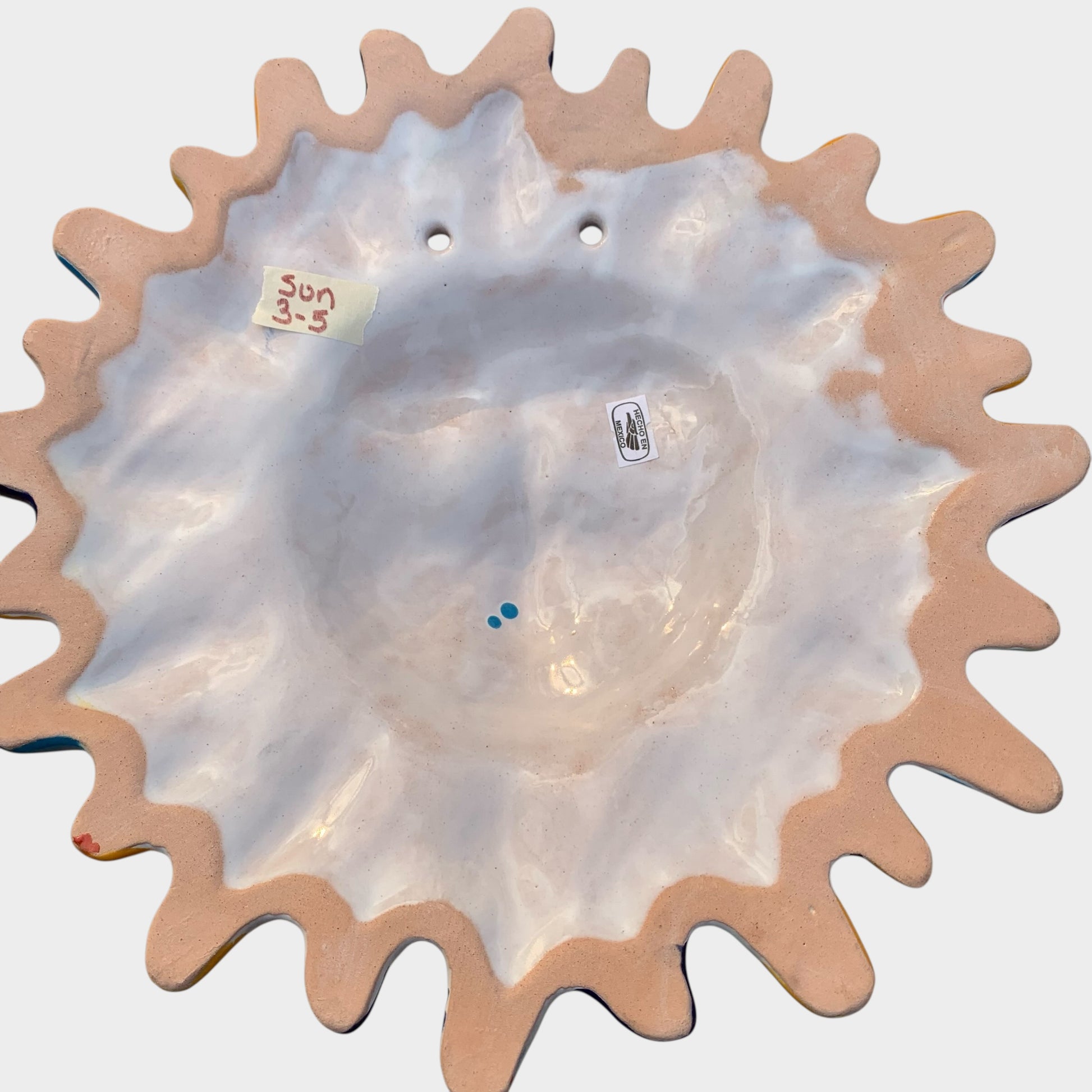 Decorative Talavera sun-shaped wall art with colorful face design on a white background Back view