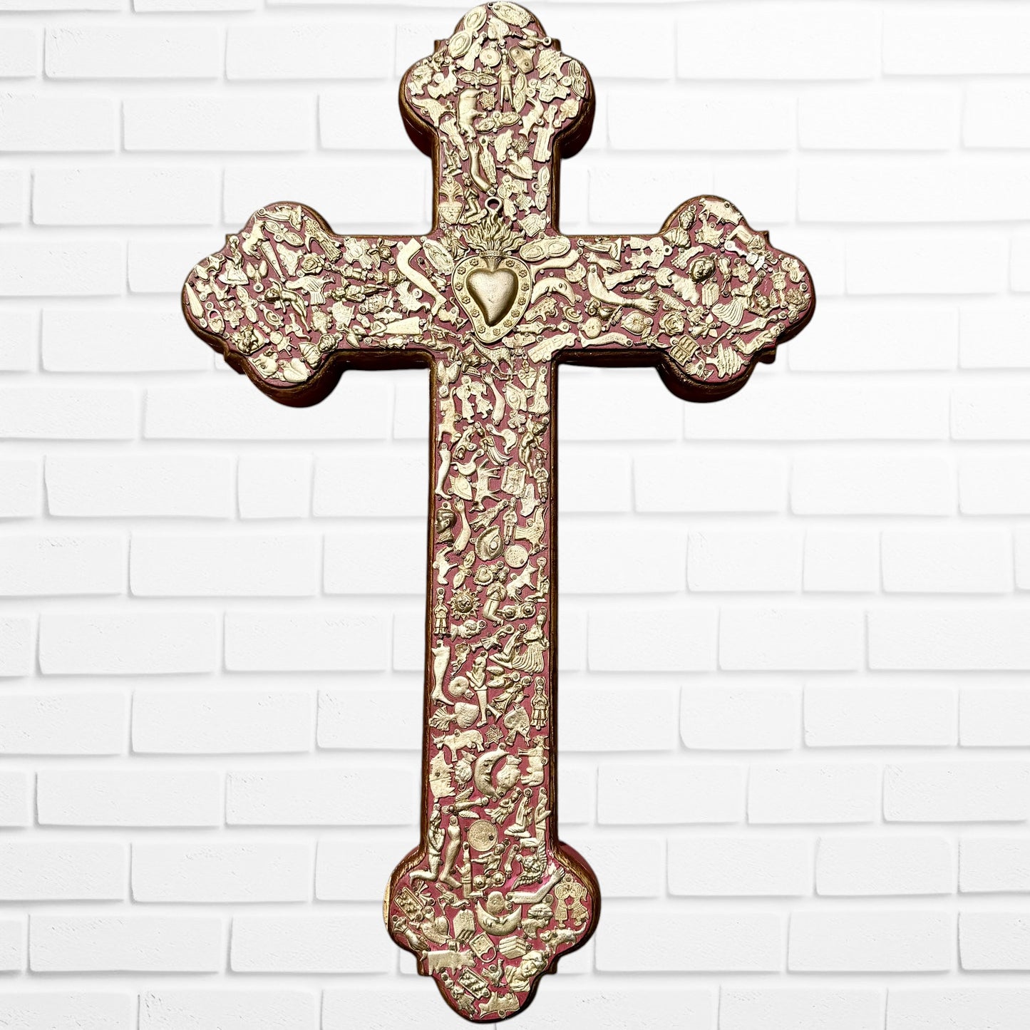 Decorative Milagros wood cross with many charms “miracles” on a white brick wall background
