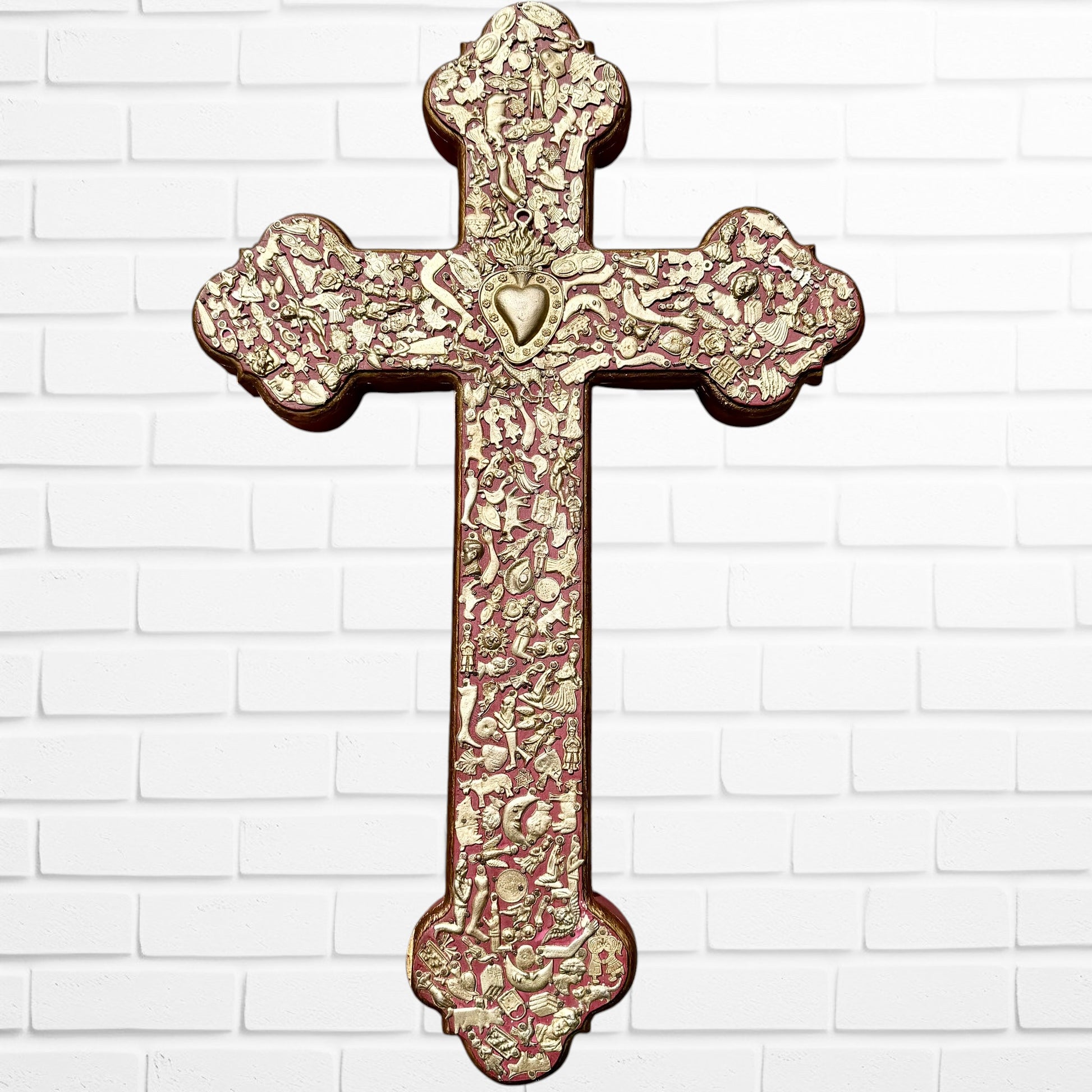 Decorative Milagros wood cross with many charms “miracles” on a white brick wall background