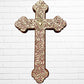 Decorative Milagros wood cross with many charms “miracles” on a white brick wall background