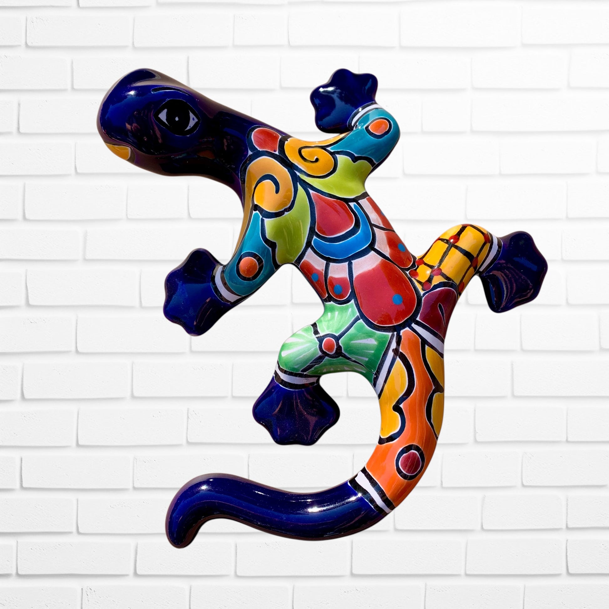 Colorful ceramic lizard wall art against a white brick wall background
