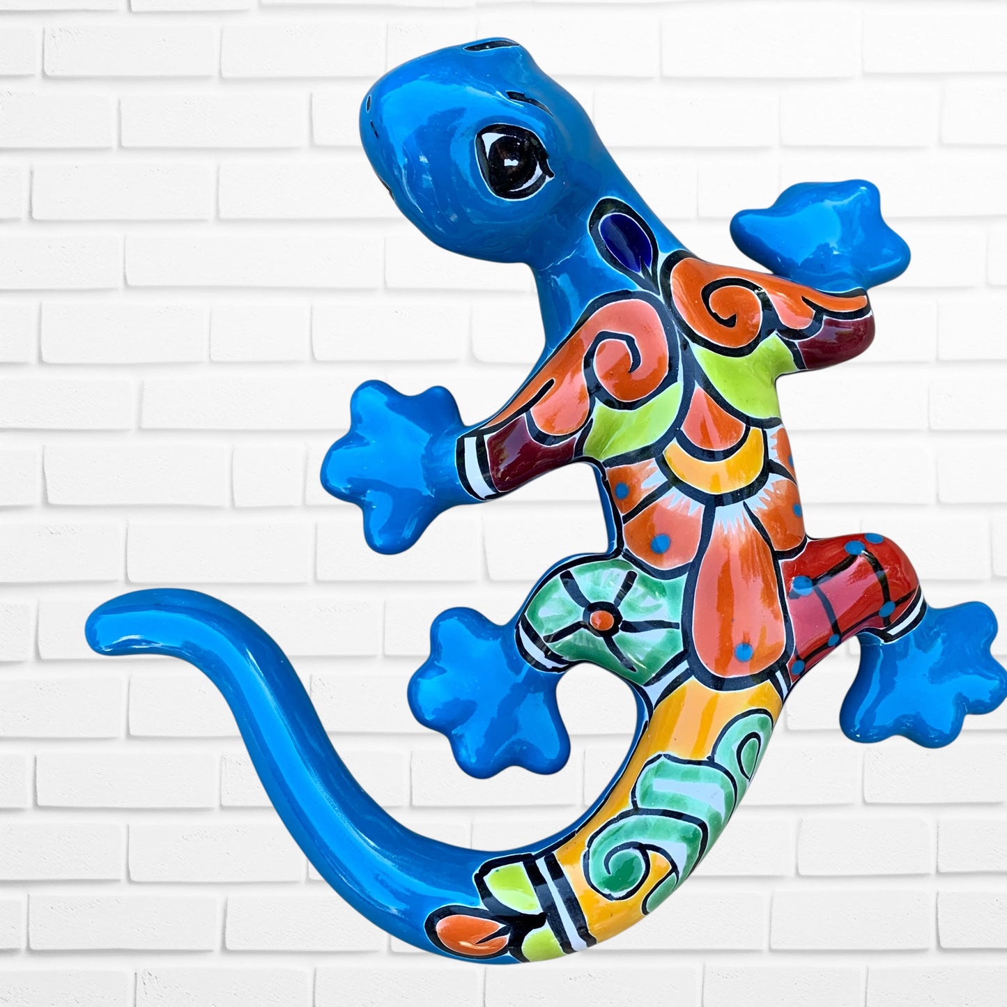 Colorful ceramic lizard wall art against a white brick wall background