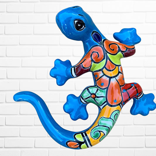 Colorful ceramic lizard wall art against a white brick wall background
