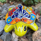Colorful Mexican Talavera ceramic turtle figurine on a natural stone background Front view