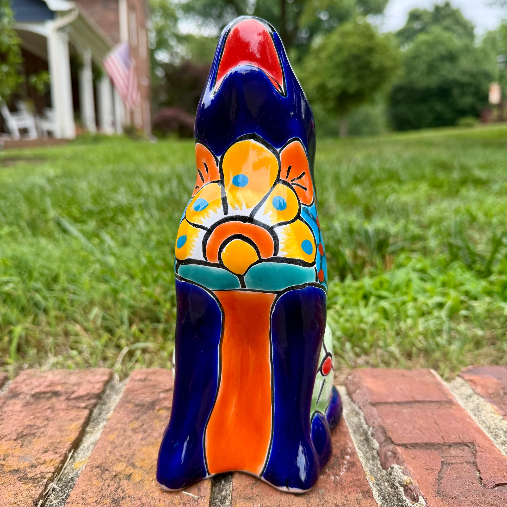 Coyote figurine on a brick surface with a garden background Front view