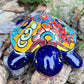 Colorful Mexican Talavera ceramic turtle figurine on a natural stone background Front view