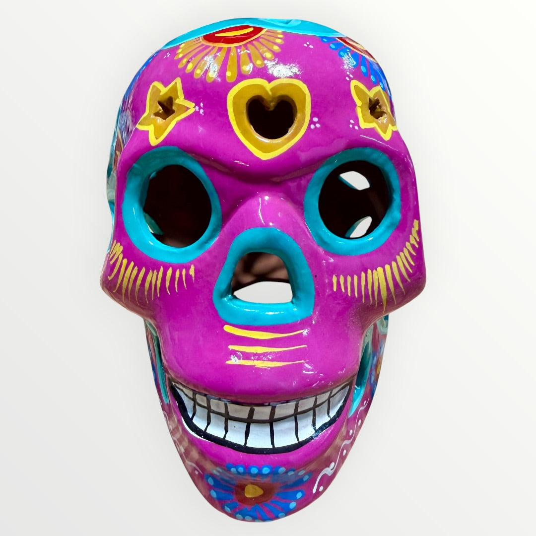 A hand-painted ceramic sugar skull in vibrant purple, turquoise blue, and yellow, decorated with floral and geometric patterns on a plain white background front face view