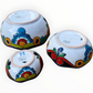 A set of three nested Talavera ceramic bowls with a vibrant hand-painted floral and geometric pattern in multiple colors, featuring a deep blue rim, shown on a plain white background, back side view.