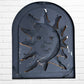 Decorative wall art of a sun and moon face with a metal frame on a white brick wall. Designed by artist Andres Martin back
