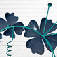 Decorative metal wall art with three blue flowers and a colorful hummingbird on a white brick background hanging loop