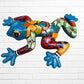 A colorful, glossy frog wall sculpture with a vibrant mosaic pattern in blue, green, orange, red, and yellow, mounted on a white brick wall.