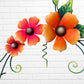 Decorative wall art with three orange flowers and hummingbird on a white brick wall background showing flower close up