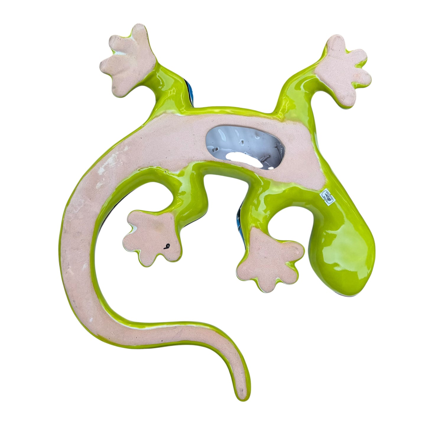 A colorful decorative lizard Talavera wall sculpture with a hand-painted floral and geometric pattern, mounted against a white brick wall, back with hanging hole.