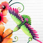 Decorative metal wall art with orange flowers and a hummingbird on a white brick background bird close up