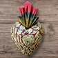 A Mexican Milagros medium heart in red with a gold and red flaming top, covered in antiqued golden charms. #7-1