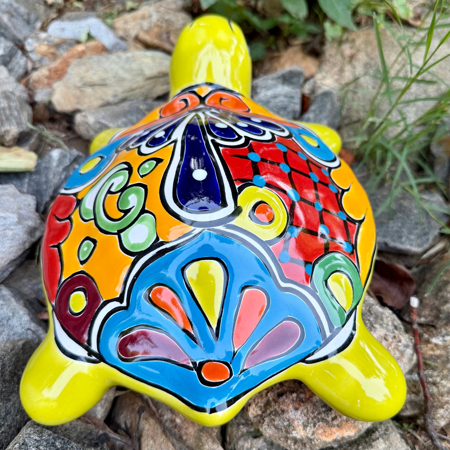 Colorful Mexican Talavera ceramic turtle figurine on a natural stone background Back view