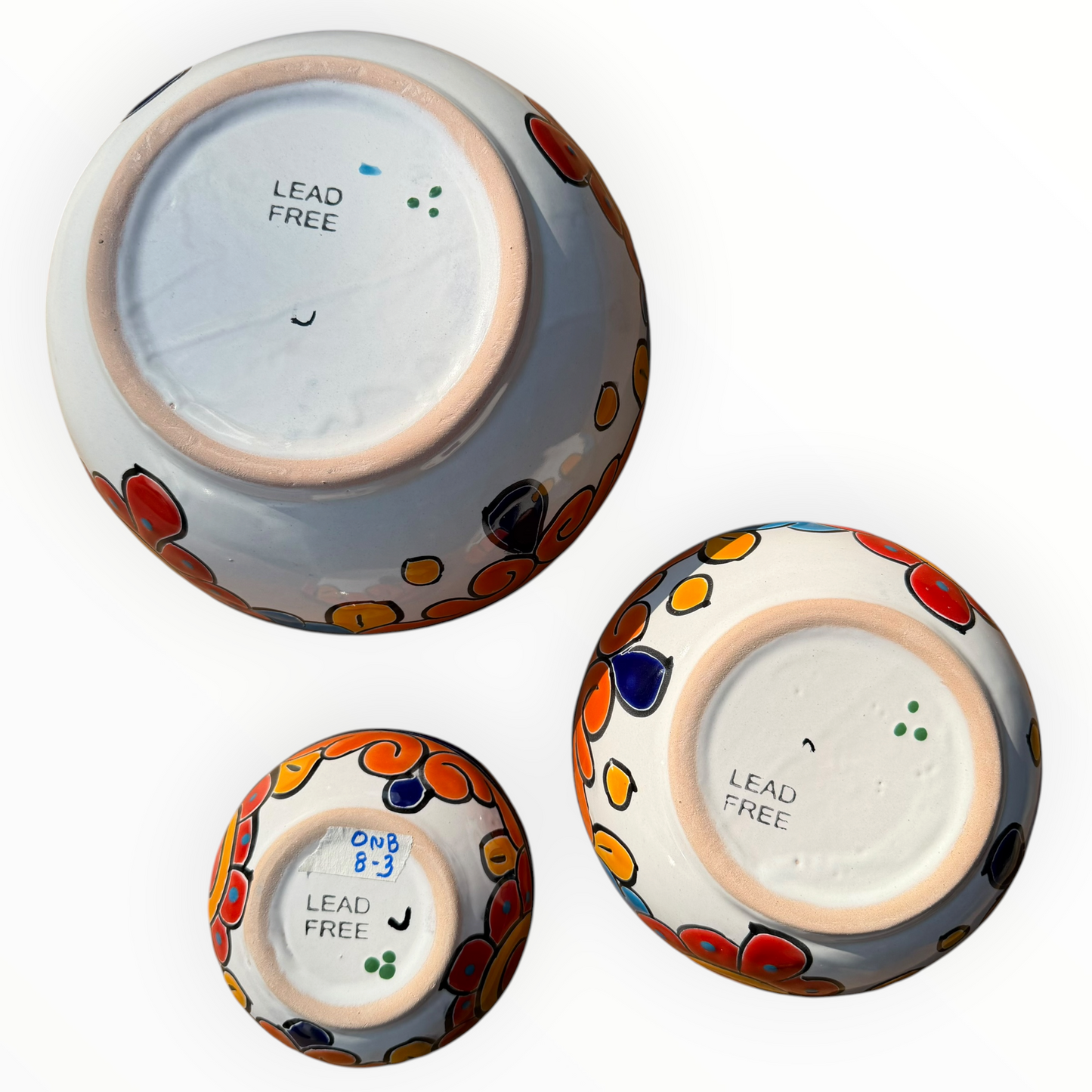 A set of nested, round Talavera ceramic bowls decorated with a vibrant, hand-painted Mexican Talavera style pattern featuring blue, yellow, orange, red, and green designs on a white background, bottom view.