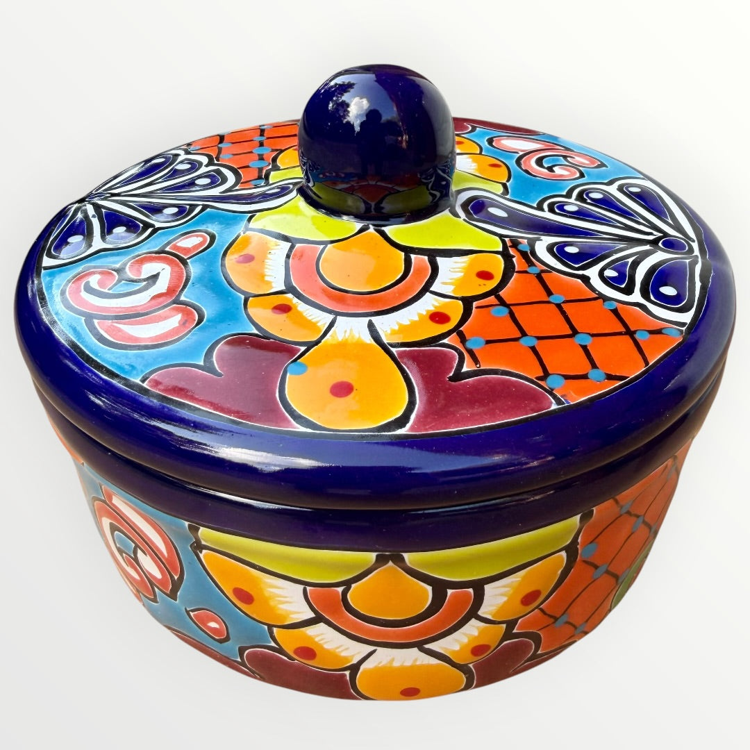 A hand-painted Talavera ceramic lidded container with a colorful Mexican-style floral pattern in blue, orange, yellow, red, and white, featuring a glossy dark blue lid knob.