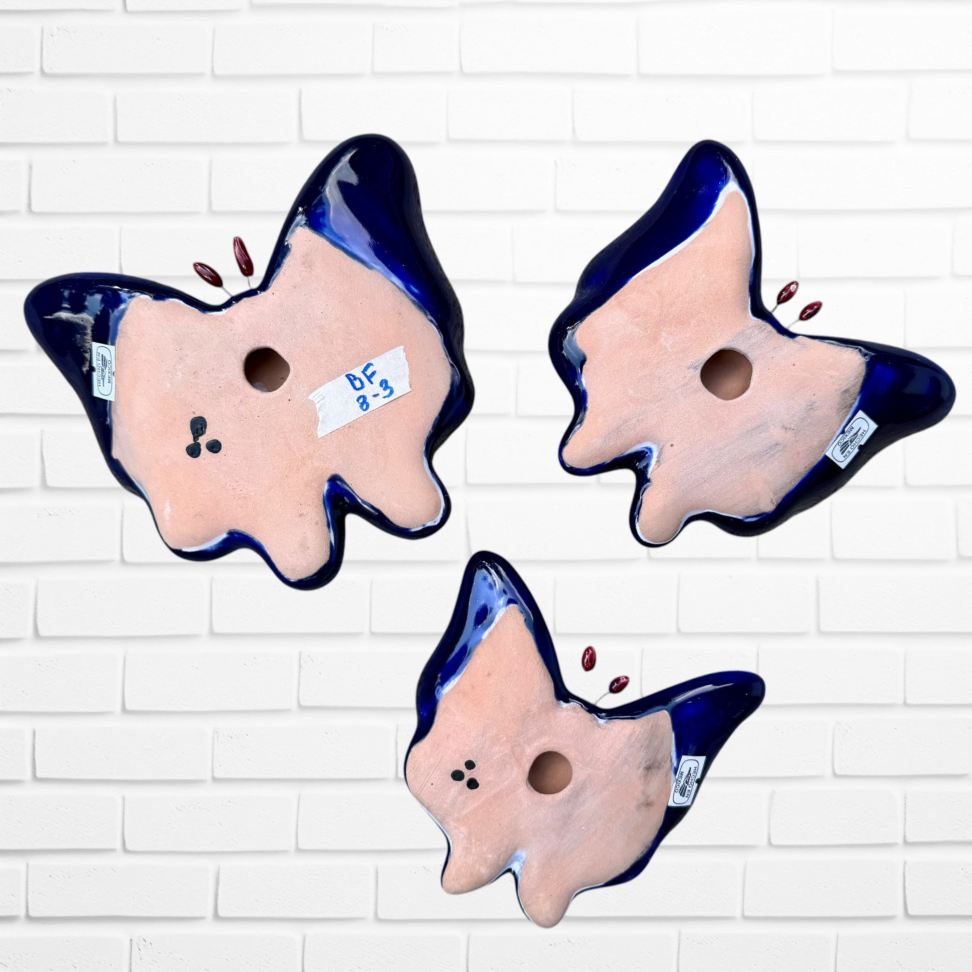 Three colorful talavera butterfly wall art pieces with blue and traditional multicolor patterns, back view.