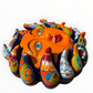 A colorful hand-painted Talavera ceramic sun wall sculpture with big wavy rays on a plain white background, left side view.