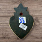 A decorative Milagros Sacred Heart featuring a black and silver painted heart adorned with charms, set against a rustic wood background, this is the back view.