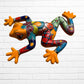 A colorful hand-painted ceramic frog wall sculpture in a dynamic leaping pose, set against a white painted brick wall background.
