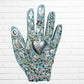Decorative wall art of a hand with various small figurines and symbols on a white brick background light blue three