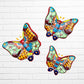 Three colorful ceramic Talavera butterfly wall art pieces with orange, blue, green, yellow, and purple mosaic patterns, displayed against a white brick wall.