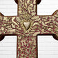 Decorative Milagros wood cross with many charms “miracles” on a white brick wall background Center heart 