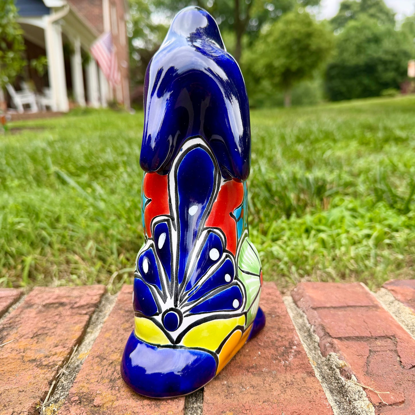 Coyote figurine on a brick surface with a garden background Back view