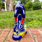 Coyote figurine on a brick surface with a garden background Back view