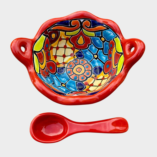 Colorful talavera salsa bowl with floral patterns and spoon on a white background