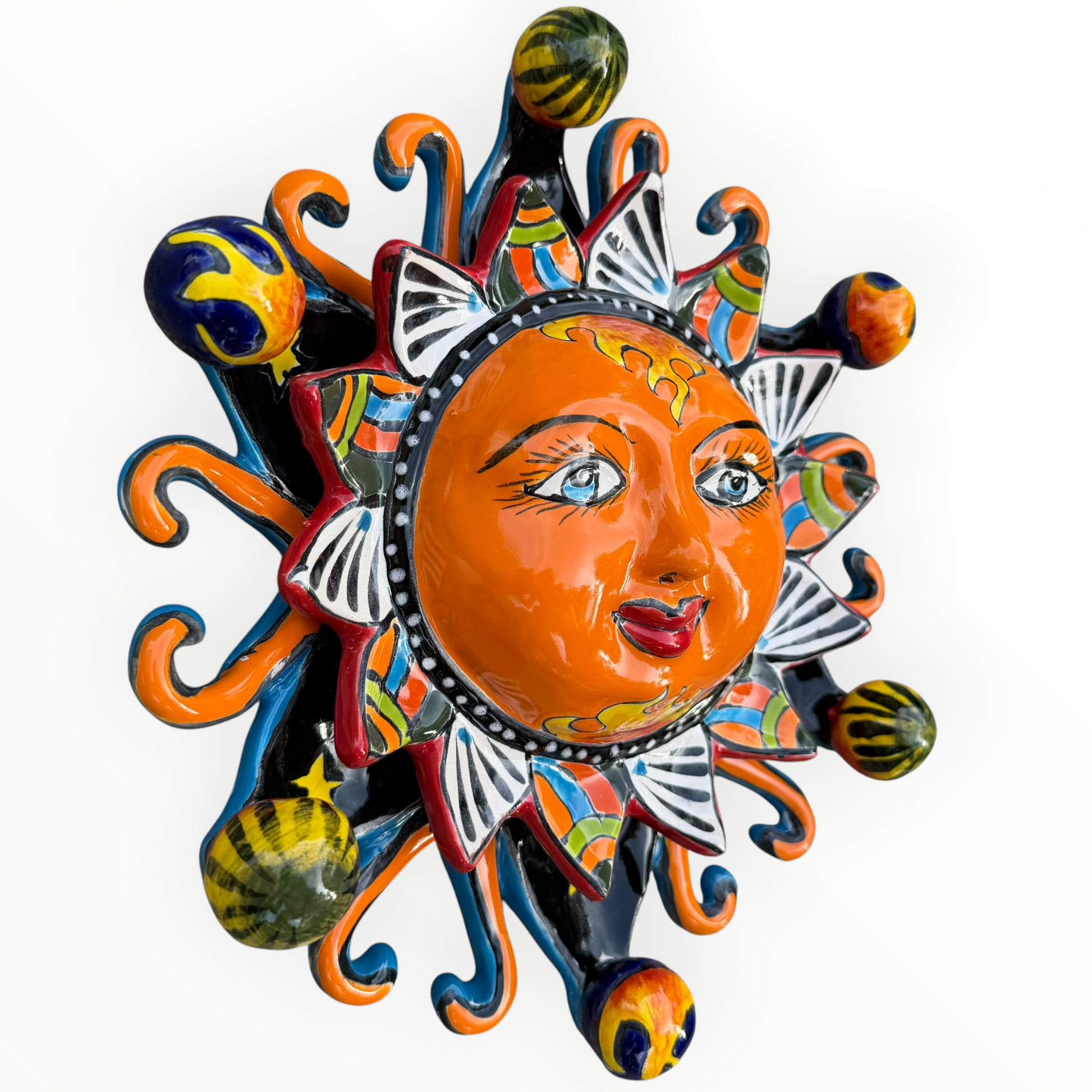 A colorful hand-painted Talavera ceramic sun wall decor piece with a smiling face, orange center, planets, and multicolored rays on a plain white background left side view three dimensional.