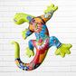 A colorful decorative lizard Talavera wall sculpture with a hand-painted floral and geometric pattern, mounted against a white brick wall, right side view.