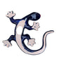 A colorful Mexican Talavera wall sculpture of a lizard, featuring a vibrant multicolor pattern with dark blue, orange, red, green, and yellow, mounted on a white brick wall, back showing hanging hole.